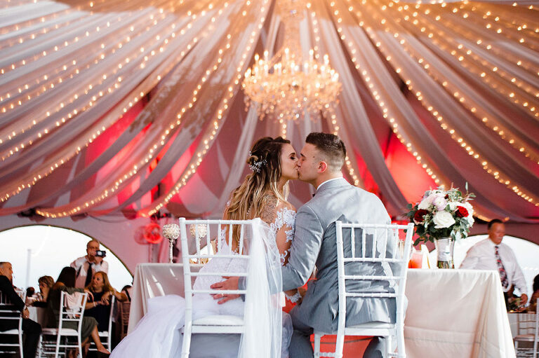 uplighting and chandelier at Herrington on the Bay tent wedding kiss