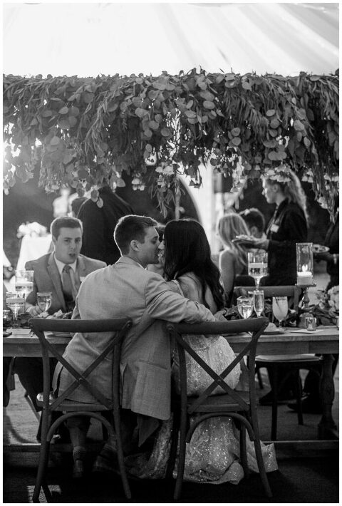 candid black and white bride and groom kiss at dinner