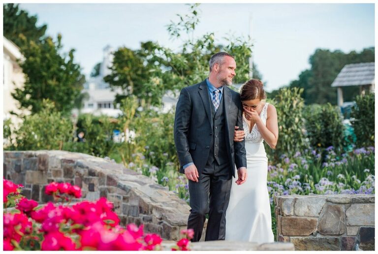 bride and groom on stone bridge in garden at Annapolis waterfront wedding venue Herrington on the Bay pink flowers and plaid tie for groom