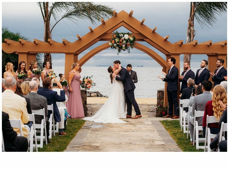 wedding kiss at Herrington on the Bay Annapolis waterfront wedding under pergola brides maids in mauve
