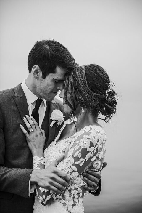 moody black and white wedding photo tender kiss by water