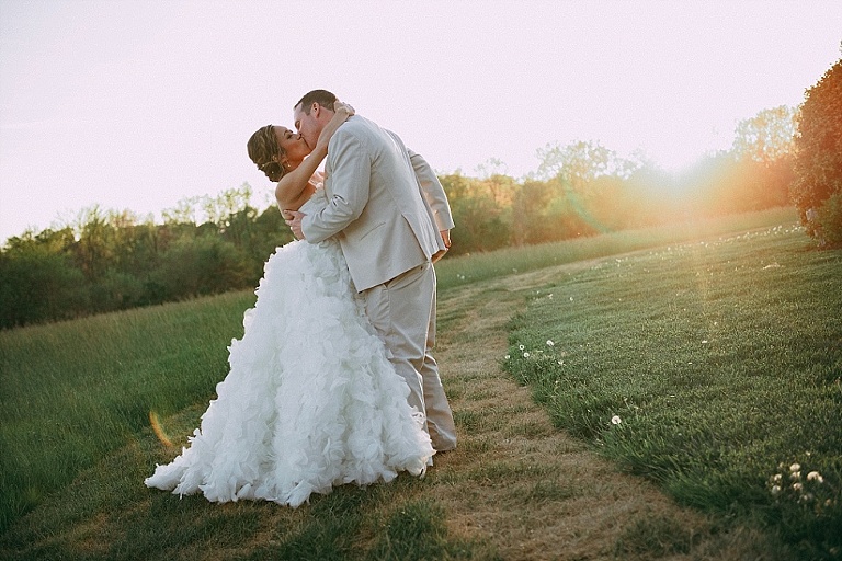 ruffled train wedding dress at sunset with groom kissing at Kent Island Resort in field